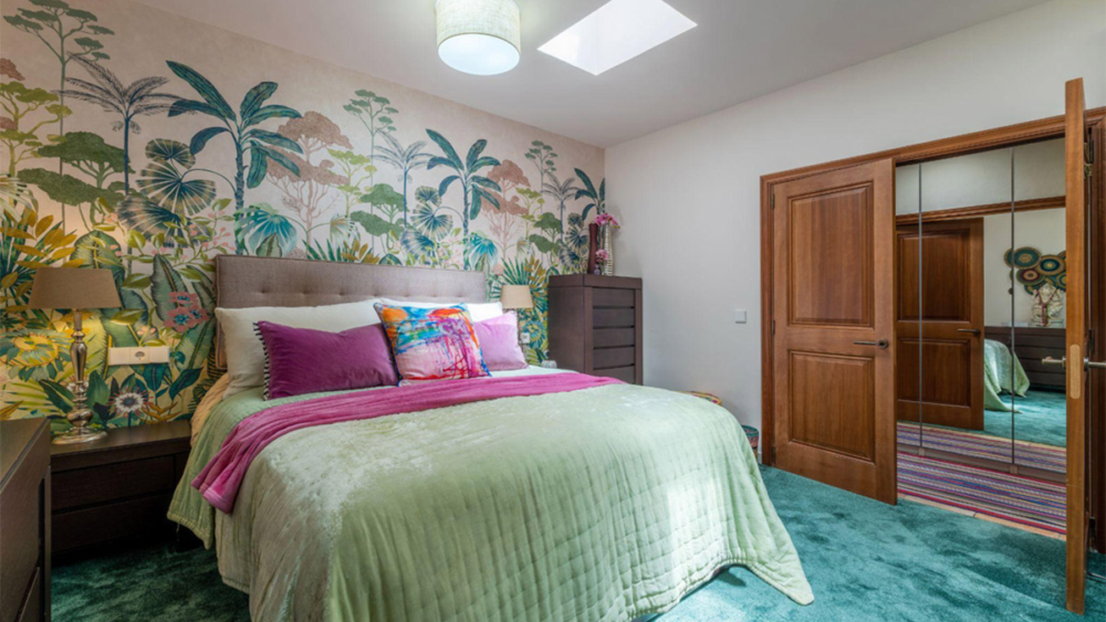Guest bedroom with botanical wallpaper, mint bedding and a walk-in wardrobe in Mallorca