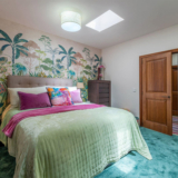 Guest bedroom with botanical wallpaper, mint bedding and a walk-in wardrobe in Mallorca