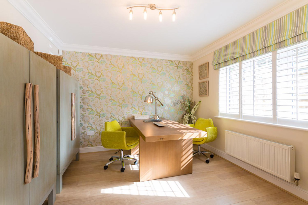 Creative workspace with a wooden table, lime-green chairs and patterned wallpaper